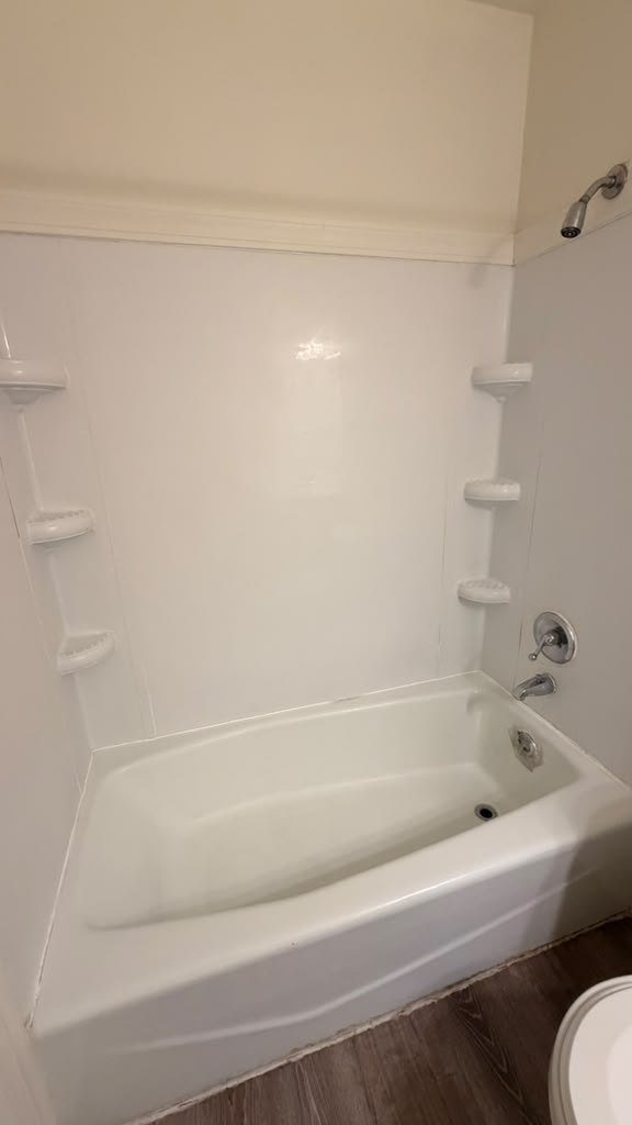 Spotless shower walls and corner shelves above the tub